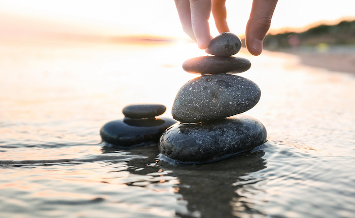 person stacking stones in the ocean