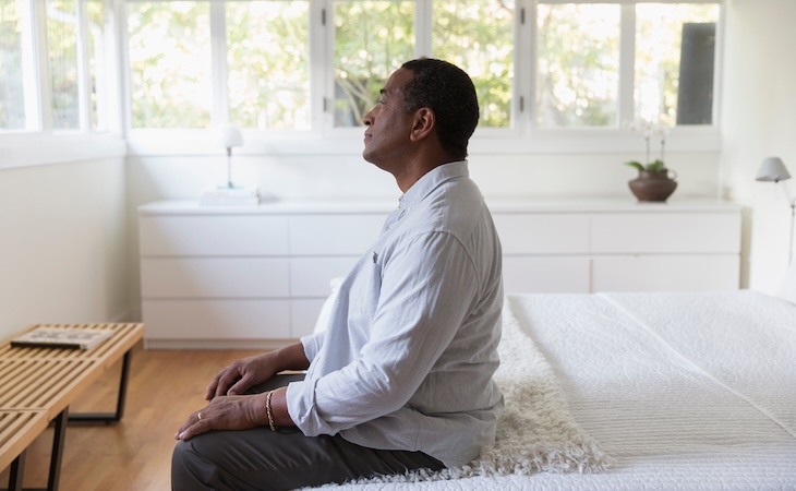 senior person sitting on edge of bed