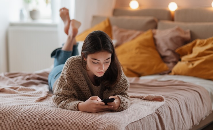 Young teenage girl srolling her smartphone in the room.