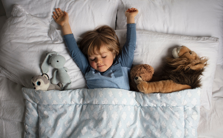 Child sleeping blissfully in bed with stuffed animals